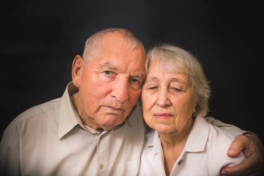 Sad elderly couple on a the black background
