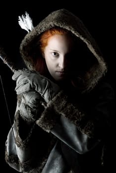 girl archer in a costume with bow isolated in a dark background