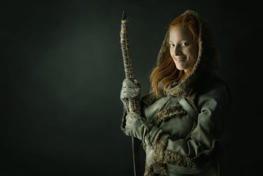 girl archer in a costume with bow isolated in a dark background