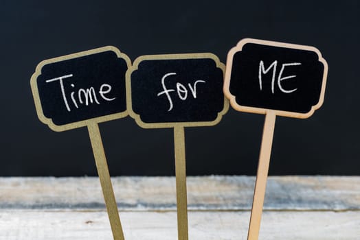 Concept message TIME FOR ME written with chalk on wooden mini blackboard labels, defocused chalkboard and wood table in background