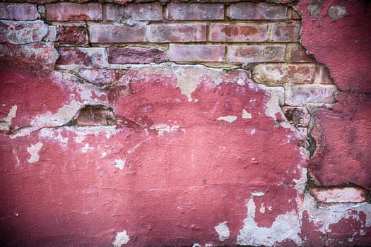 Decaying wall grunge texture. Red paint and exposed brick with plaster falling off