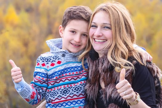 Mother and son showing ok sign stand outdoors in nature