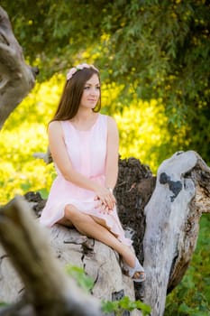 Beautiful girl sitting on a fallen tree in the forest