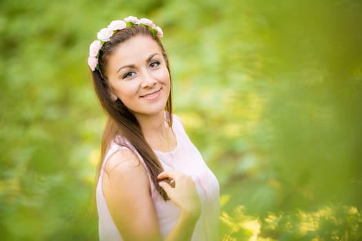 Portrait of a young beautiful girl on a blurred background of green foliage