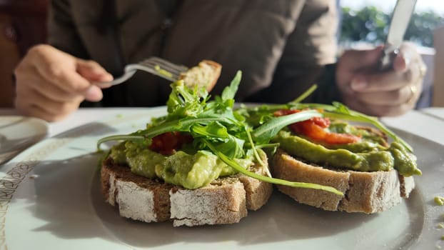 Diners savor fresh avocado toast topped with greens in a cafe.