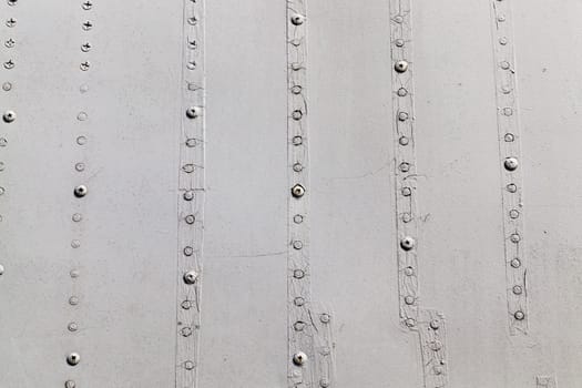 photographed close-up of an old lining of the aircraft. gray surface with screws, some of which are welded