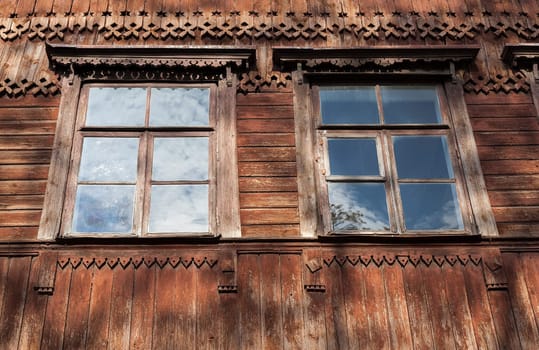 photographed close-up of the old red wooden houses with windows. In the house no one lives