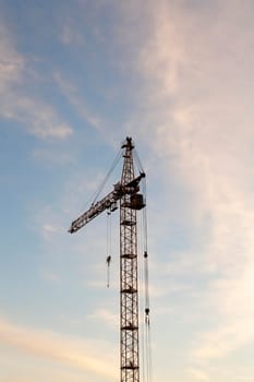 photographed close-up construction cranes during construction of a new multi-storey apartment building, blue sky and clouds