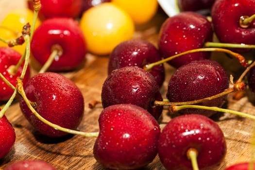 Photographed close-up ripe red cherries covered with drops of water, little depth of field, berries are on the wooden table