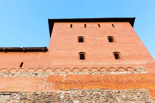 Tower of an ancient fortress made of red brick. Photo close-up, on background blue sky