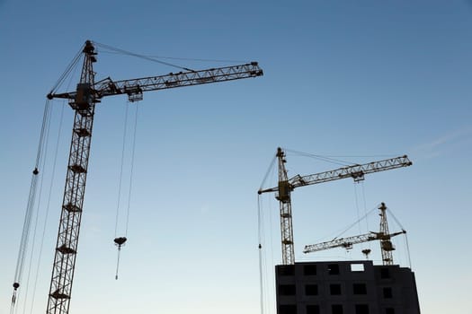 photographed close-up construction cranes during construction of a new multi-storey residential building