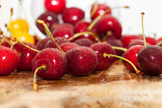 Photographed close-up ripe red cherries covered with drops of water, little depth of field, berries are on the wooden table