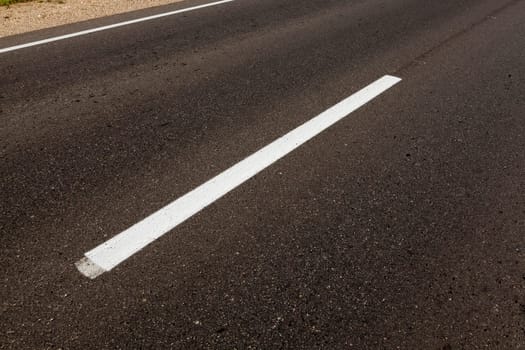 photographed close-up of road marking is located on the roadway, white line on the pavement