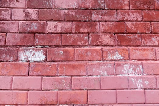 photographed close-up part of the wall of brick, painted in red color, which has been spoiled with time
