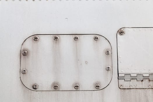 photographed close-up of an old lining of the aircraft. gray surface with screws, some of which are welded