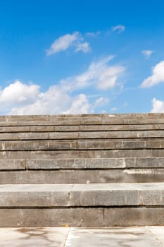 photographed close-up stairs to the street. The structure is made of concrete slabs. In the background, blue sky with clouds