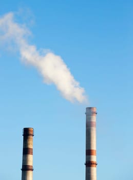 power plant with smoke pipe during operation. Photo from a distance close-up. Blue sky in autumn season