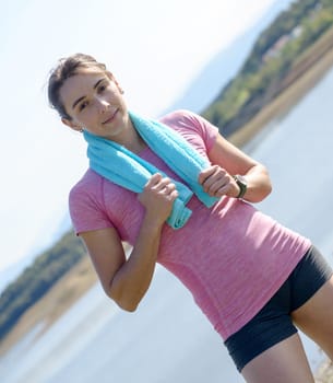 portrait of young sporty woman with blue towel in the countryside