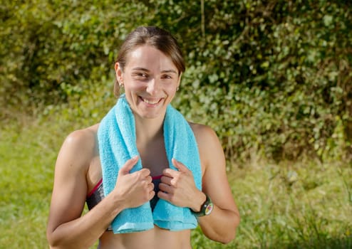 portrait of young sporty woman with blue towel in the countryside