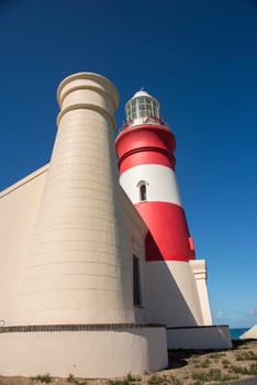 A view of Cape Agulhas Lighthouse from the side with one of the towers in the foreground.