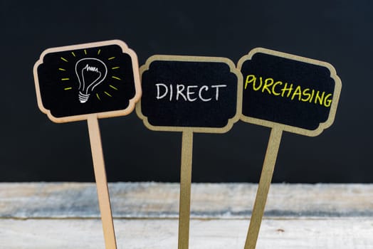 Concept message DIRECT PURCHASING and light bulb as symbol for idea written with chalk on wooden mini blackboard labels, defocused chalkboard and wood table in background