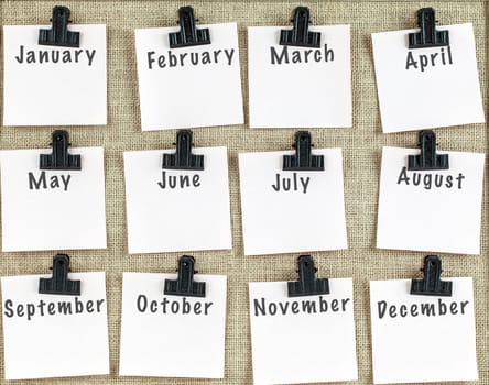 Notice board with twelve clips and note paper showing all months of the year. Blank space for more text