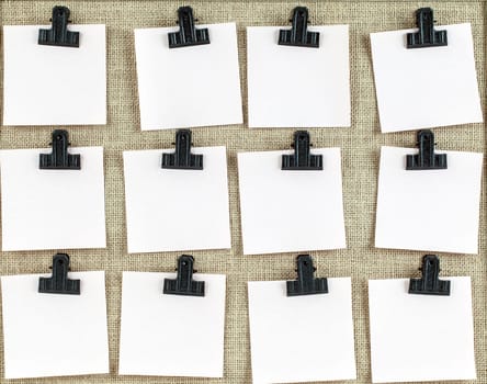 Notice board with twelve clips and blank note paper. Empty space for more text on each square.