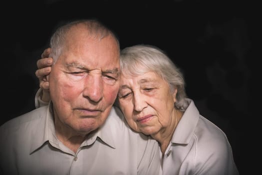 Sad elderly couple on a the black background