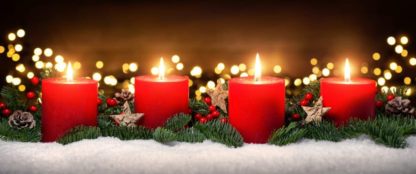 Festive studio shot of elegant advent decoration with fir branches on snow and four burning red candles,dark wood background with bokeh lights
