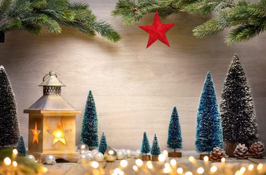 Christmas scene background with a lantern,trees,fir branches,red star and blurred lights in front of a wooden board as copy space