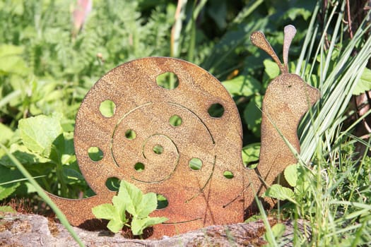 A snail made of rusted metal for garden decoration.