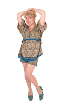 A middle age blond woman standing in shorts from the front, .with her hands on her head, isolated for white background..