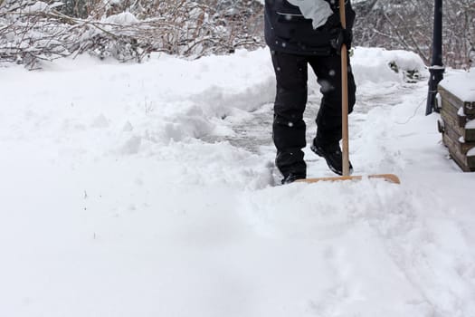 A man clears snow from a footpath in winter