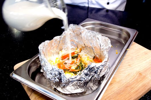 Meat with vegetables in foil on Protvino. Wooden background.