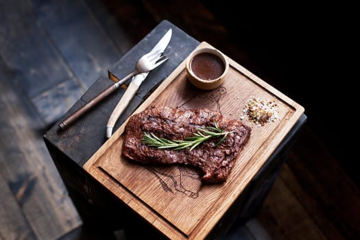 Beef steak. Piece of  Grilled BBQ beef marinated in spices and herbs on a rustic wooden board over rough wooden desk with a copy space. Top view. Stock Image