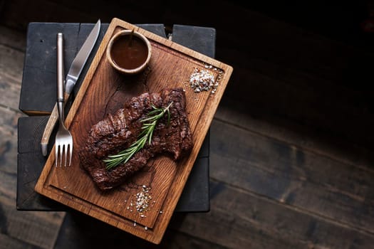 Beef steak. Piece of  Grilled BBQ beef marinated in spices and herbs on a rustic wooden board over rough wooden desk with a copy space. Top view