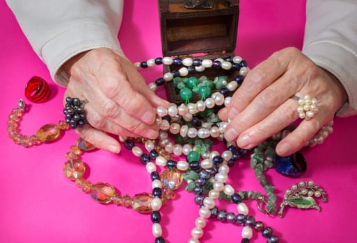 Senior woman sitting and going through in the hands of jewelry pearl