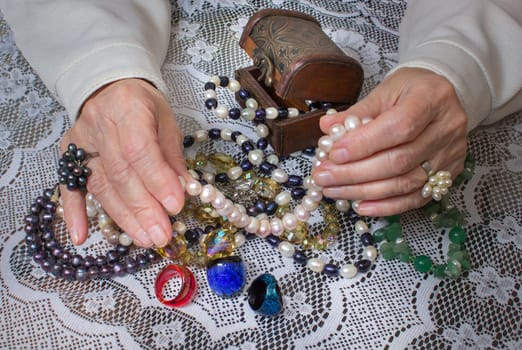 Senior woman sitting and going through in the hands of jewelry pearl