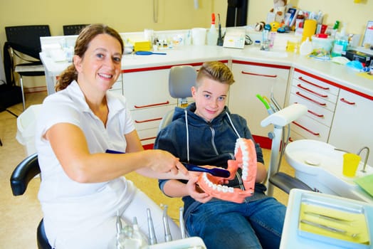 teenager is treated by female dentist in dental surgery