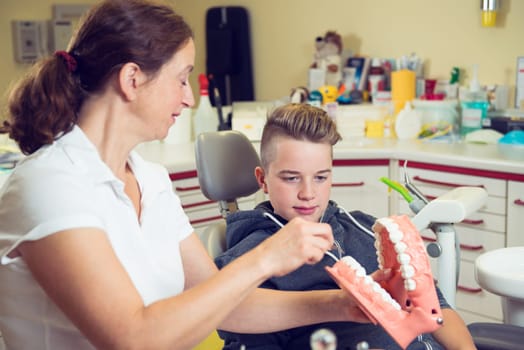 teenager is treated by female dentist in dental surgery