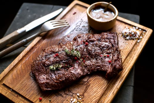 Beef steak. Piece of  Grilled BBQ beef marinated in spices and herbs on a rustic wooden board over rough wooden desk with a copy space. Top view. Stock Image