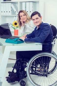 disabled businessman in wheelchair and his female colleague
