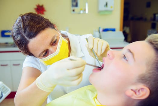 teenager is treated by female dentist in dental surgery