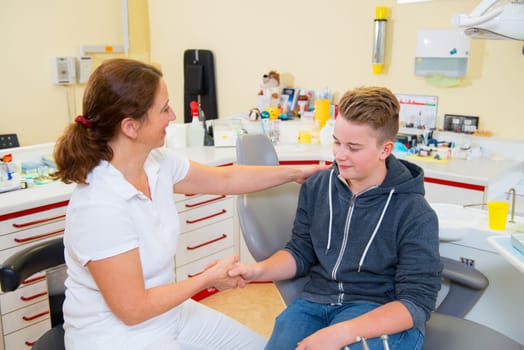 teenager is treated by female dentist in dental surgery
