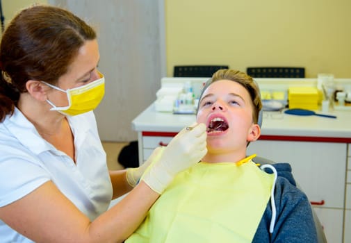 teenager is treated by female dentist in dental surgery