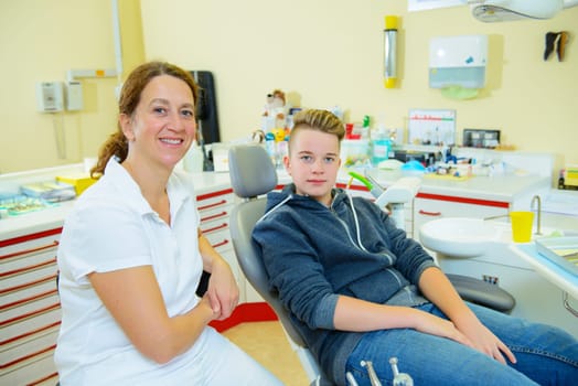 teenager is treated by female dentist in dental surgery