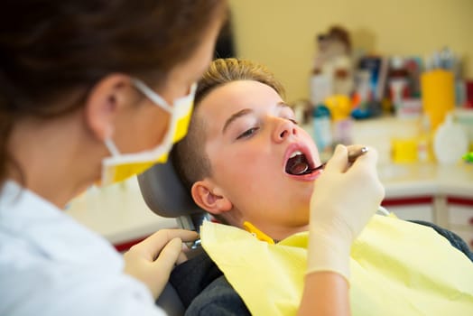 teenager is treated by female dentist in dental surgery