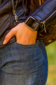 Young girl wears smart watch with hand in pocket. Focus on smart watch!