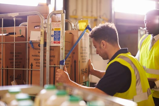 Man preparing roll cages for delivery, watched by supervisor
