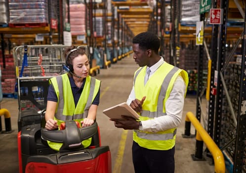Warehouse manager instructing woman operating tow tractor